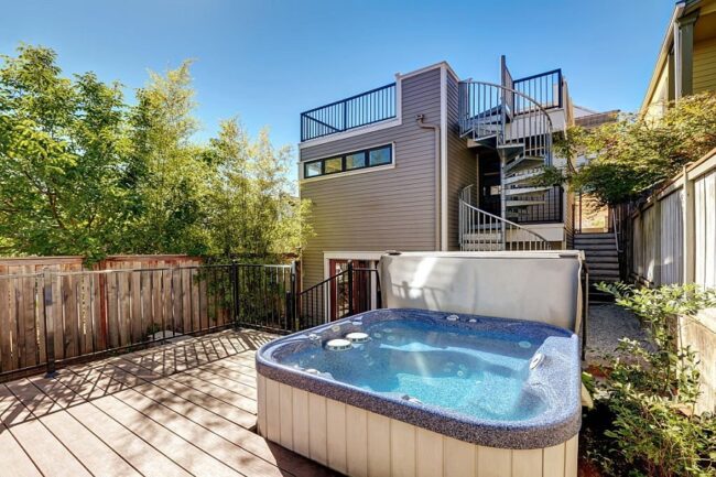 Wooden walkout deck with hot tub. House exterior in Tacoma. Northwest, USA Small Hot Tubs vs. Large Hot Tubs