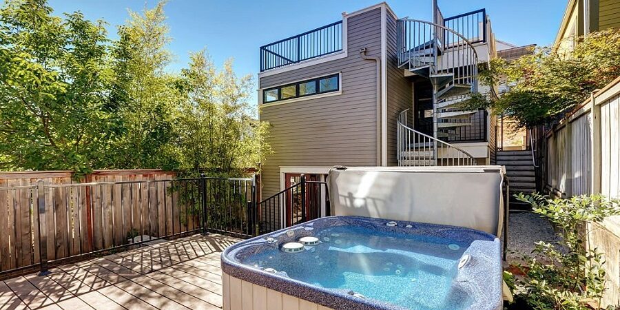 Wooden walkout deck with hot tub. House exterior in Tacoma. Northwest, USA Small Hot Tubs vs. Large Hot Tubs